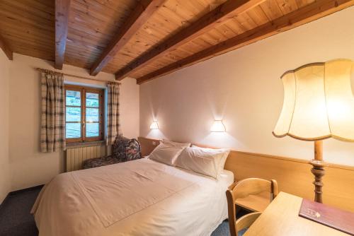 a bedroom with a bed and a table with a lamp at Locanda La Clusaz in Gignod