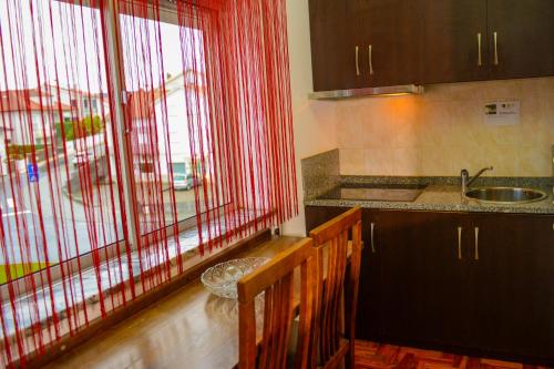 a kitchen with red curtains and a sink and a window at SEIA Apartamentos Serra da Estrela in Seia