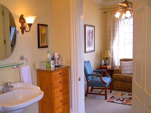 a bathroom with a sink and a mirror and a chair at Lyndon House Bed & Breakfast in Lexington