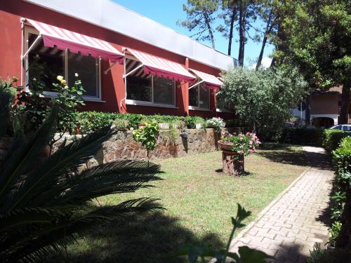 a red house with a garden and a brick walkway at Hotel Grifone in Principina a Mare