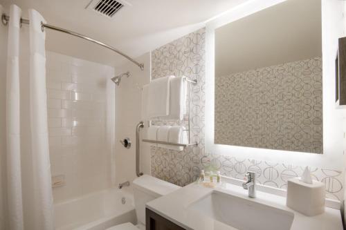 a white bathroom with a sink and a tub at Holiday Inn Denver East, an IHG Hotel in Denver
