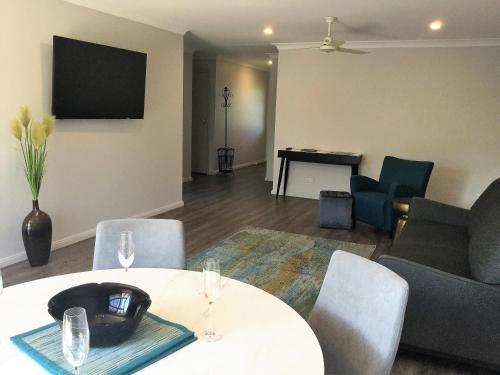 a living room with a table and chairs and a piano at Tic Tac Toe Quality Accommodation in Armidale