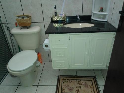 a bathroom with a white toilet and a sink at Condomínio Vila Paradiso in Serra Negra