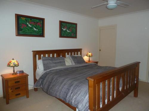 - une chambre avec un lit en bois et 2 lampes sur les tables dans l'établissement Blackwattle at Barrington Tops, à Bandon Grove