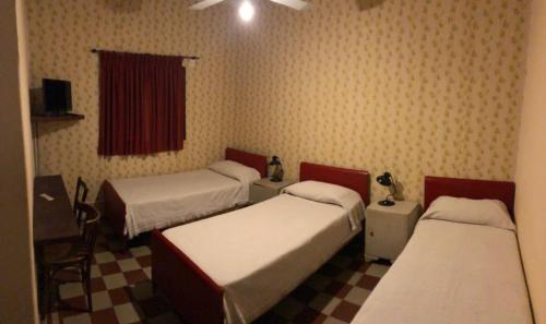 Una habitación con tres camas y un televisor. en Hotel Aguirre, en Mina Clavero