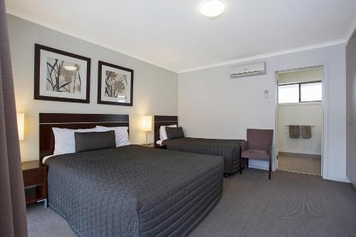 a hotel room with a bed and a chair at Elm Tree Motel in Warrnambool