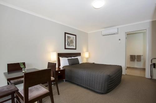 a bedroom with a bed and a table and a desk at Elm Tree Motel in Warrnambool