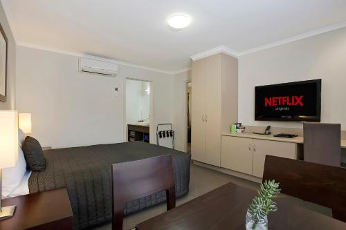 a hotel room with a bed and a tv at Elm Tree Motel in Warrnambool