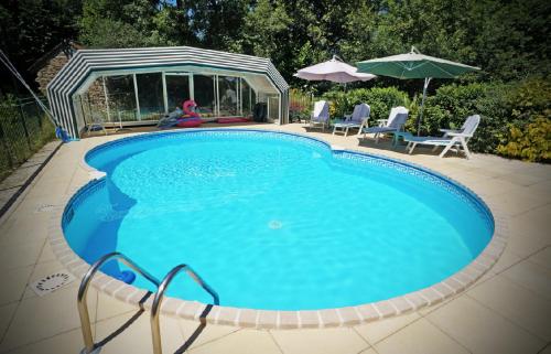 a large blue swimming pool with chairs and umbrellas at La Coterie Lodges in Blaudeix