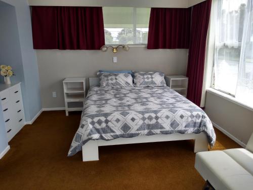a bedroom with a bed with a gray and white comforter at Ironsands B&B in Patea