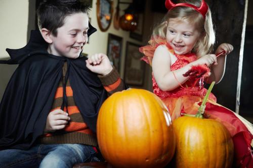 a boy and a girl dressed in costumes sitting next to pumpkins at Garryvoe Hotel in Ballycotton