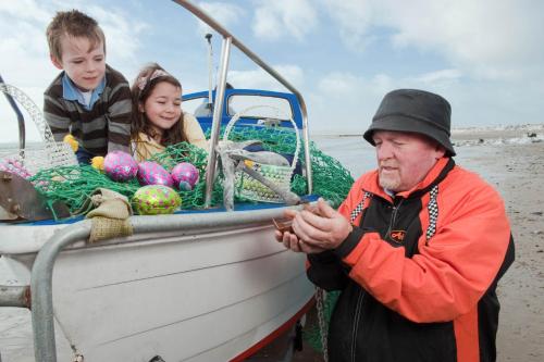 a man is standing in a boat with two children at Garryvoe Hotel in Ballycotton