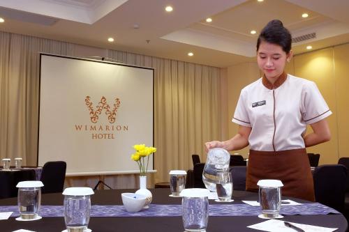 a woman standing in front of a table with water at Wimarion Hotel Semarang in Semarang