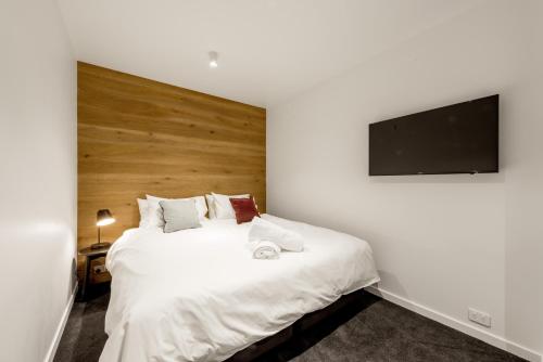 a bedroom with a large white bed and a flat screen tv at Elk at Falls in Falls Creek