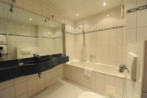 a bathroom with a tub and a sink and a toilet at Appart-Hotel-Heldt in Bremen