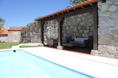 a swimming pool with a stone wall and a pergola at Casa do Nato -Turismo Rural in Viana do Castelo
