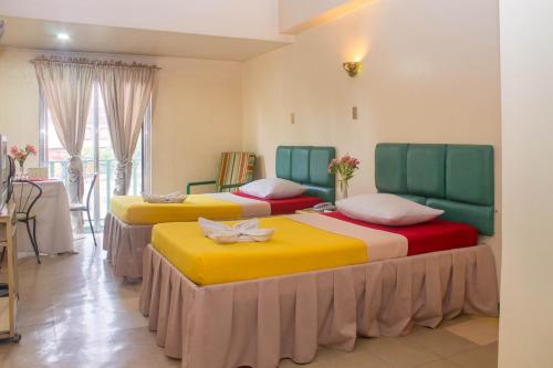 três camas num quarto com amarelo e vermelho em Benguet Prime Hotel em Baguio