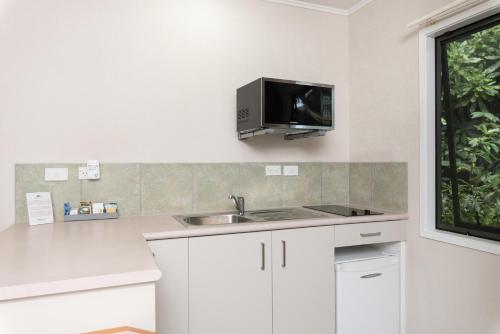 a kitchen with a sink and a tv on the wall at Kauri Park Motel in Kerikeri