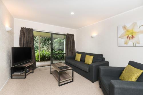 a living room with two couches and a tv at Kauri Park Motel in Kerikeri