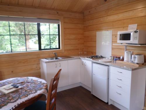 a kitchen with white cabinets and a table and a microwave at Central Chalets Ltd in Alexandra