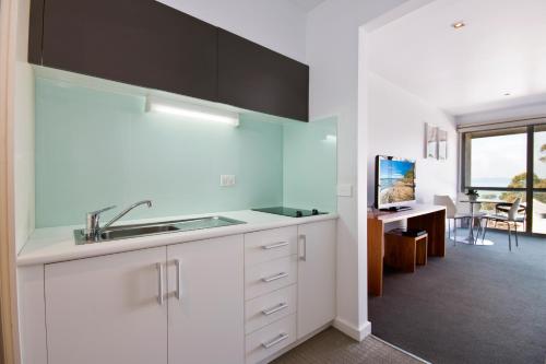a kitchen with white cabinets and a sink at Lorne Bay View Motel in Lorne