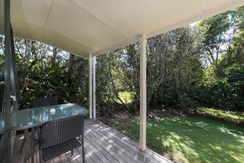 a covered porch with two chairs on a wooden deck at Kauri Park Motel in Kerikeri