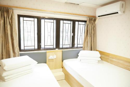 2 camas en habitación compartida con ventanas en Hoo Sang Hostel 香港豪生酒店, en Hong Kong