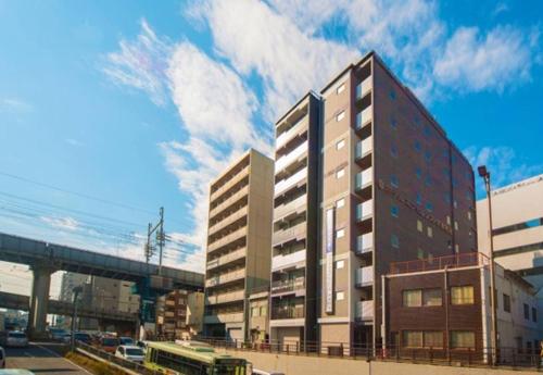 a tall building with a bus in front of it at Hotel Excellence Kyoto Station Nishi in Kyoto