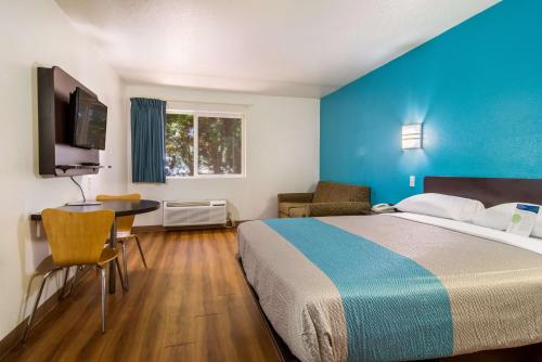 a hotel room with a bed and a desk and a tv at Motel 6 Portland Mall - 205 in Portland