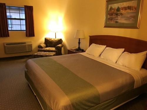 um quarto de hotel com uma cama grande e uma cadeira em Motel 6-Bloomsburg, PA em Bloomsburg