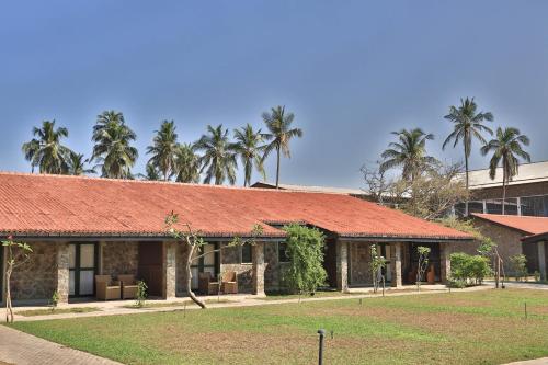 a building with a red roof and palm trees at Regenta Arie Lagoon Negombo in Negombo