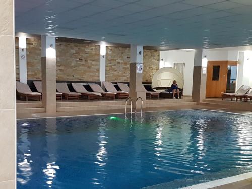 a swimming pool in a hotel with a man sitting on a couch at Milmari M18 Kopaonik in Kopaonik
