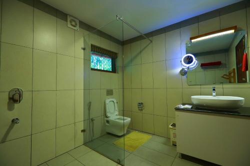 a bathroom with a toilet and a sink at Vayal Veedu - Luxury Farm Villas by the woods in Muthanga