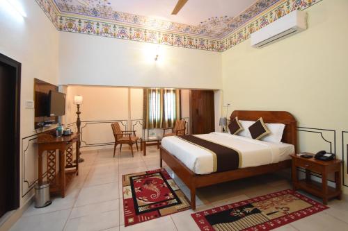 a hotel room with a bed and a tv at Virasat Mahal Heritage Hotel in Jaipur