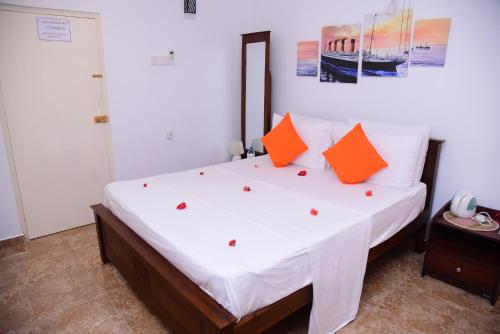 a bedroom with a large bed with orange pillows at White Villa Airport Transit Hotel in Katunayake