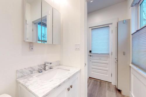 a white bathroom with a sink and a mirror at Provincetown Paradise in Provincetown