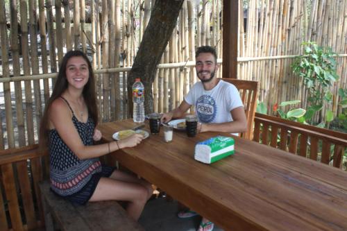 a man and a woman sitting at a wooden table at Triangle House and hot spring in Kintamani