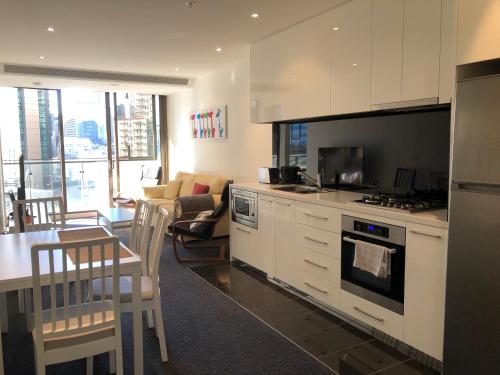 a kitchen with a stove and a dining room with a table at EPIC Private Apartment in Melbourne