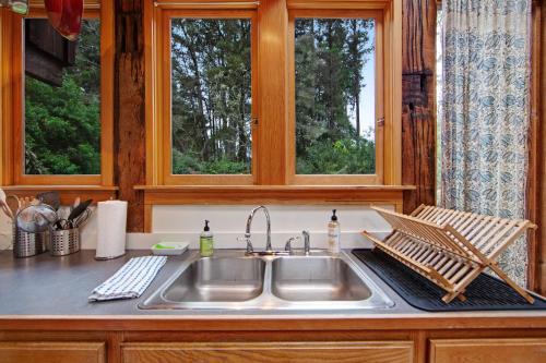 a kitchen counter with a sink and two windows at Huckleberry House in Fort Bragg