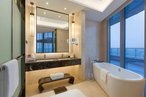 a bathroom with a tub and a large mirror at Wyndham Chongqing Yuelai in Chongqing