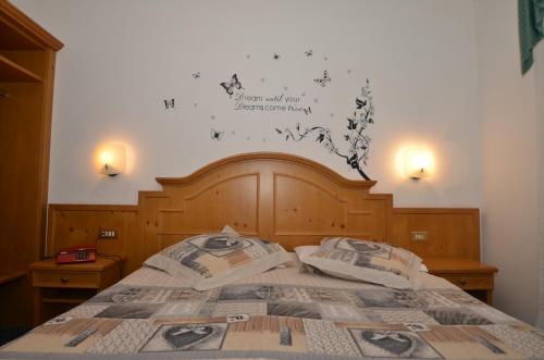 a bedroom with a bed with a sign on the wall at Hotel Albe in Rocca Pietore