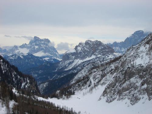 a snowy mountain range with trees and snow covered mountains at Hotel Albe in Rocca Pietore