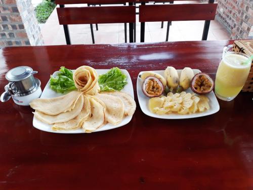 een tafel met twee borden eten en een glas sinaasappelsap bij Tam Coc Cuong Hieu Homestay in Ninh Binh