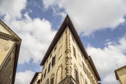 een hoog gebouw met een puntdak tegen een bewolkte hemel bij Casa Botticelli in Florence