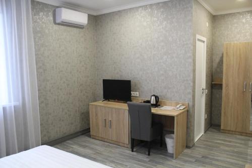 a room with a desk with a computer and a television at Hotel Inju Hills in Astana