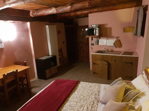 a room with a bed and a kitchen with a sink at Agriturismo Rivet d'Or in Pragelato