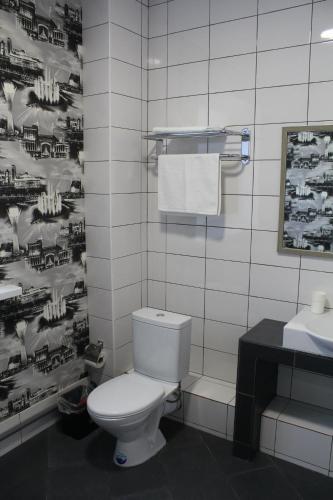 a bathroom with a white toilet and a sink at Hotel Inju Hills in Astana