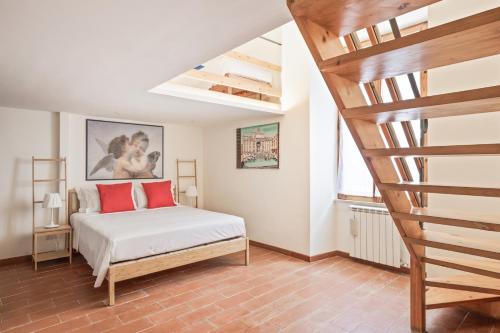 um quarto com uma cama com almofadas vermelhas e uma escada em BDC - Colosseum Superior Apartment em Roma