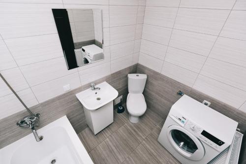a white bathroom with a toilet and a sink at Apart-Hotel in Sumy