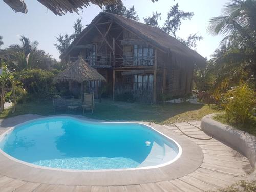a house with a large swimming pool in front of it at Baraka Beach in Vilanculos